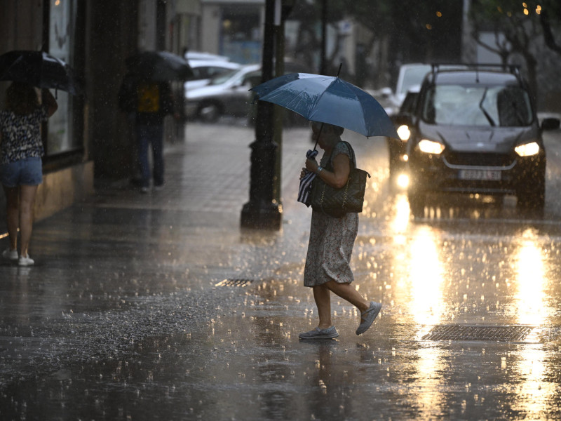 Una mujer cruza, este miércoles una calle de la ciudad de Castellón bajo una intensa lluvia