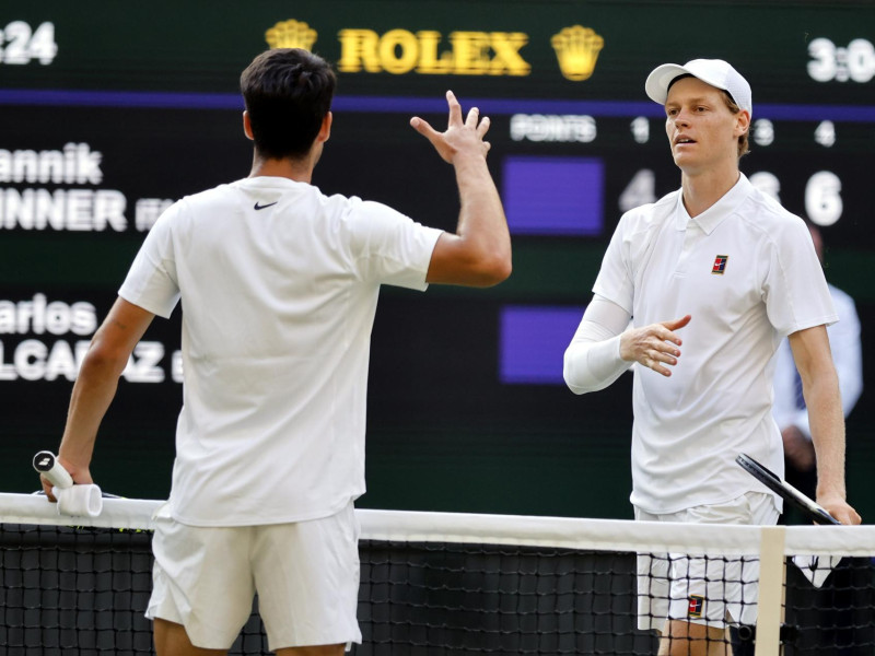 Jannik Sinner de Italia (derecha) celebra su victoria en la final individual masculina mientras estrecha la mano de Carlos Alcaraz de España en Wimbledon.