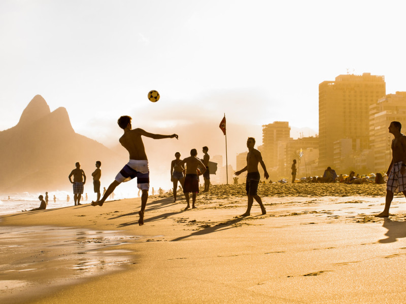 KTC36B RIO DE JANEIRO, BRAZIL - APRIL 24, 2015: Carioca Brazilians playing altinho futebol beach football kicking soccer balls at sunset Ipanema Beach on Apr