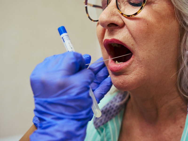 Médico realizando una prueba de hisopado bucal a una paciente mayor