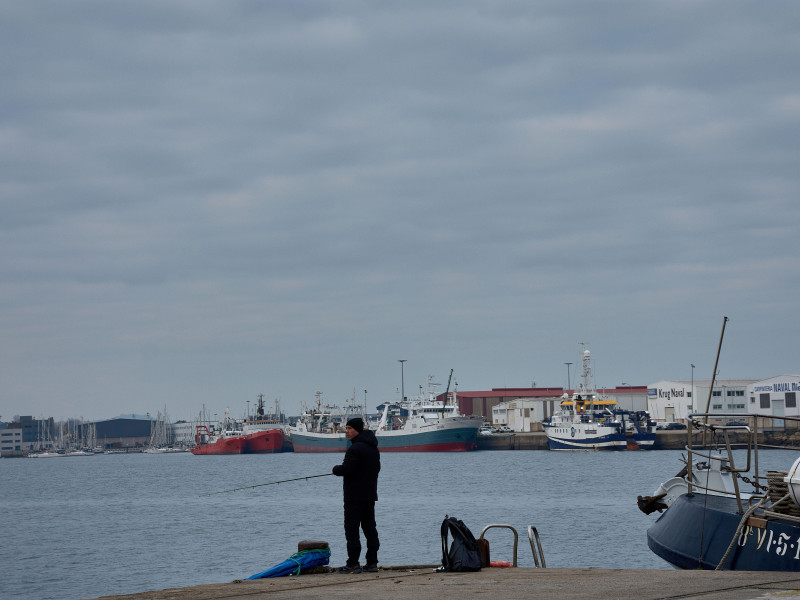 Un pescador solitario se ve de pie al borde del puerto en Orillamar, Vigo.
