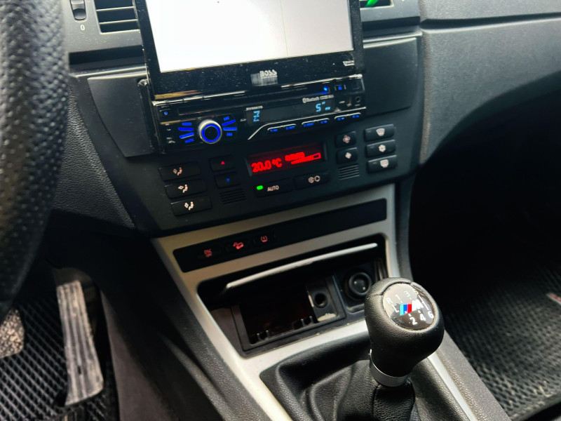 Vista interior del automóvil BMW X3 que muestra la palanca de cambios junto con la unidad de control de climatización y el sistema de entretenimiento.