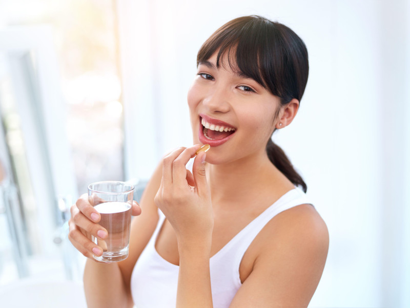 Un mujer tomando una pastilla