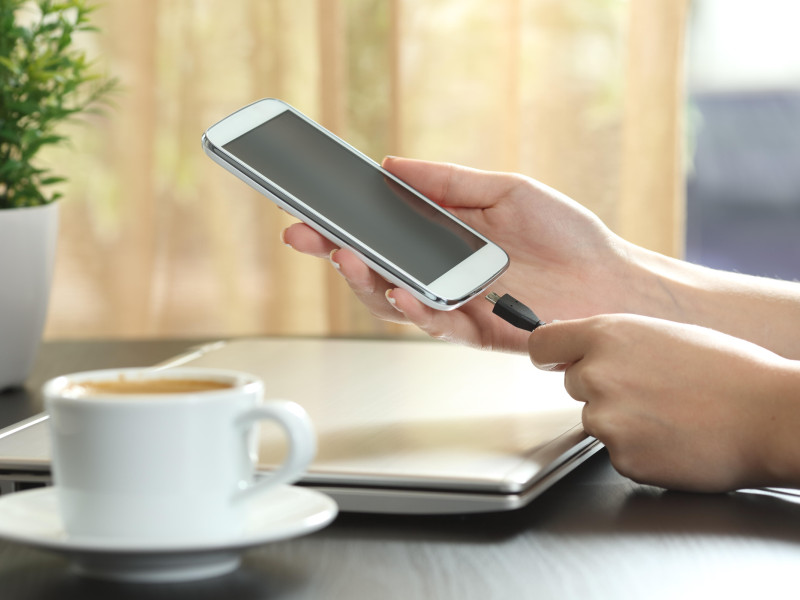 Una chica conecta su smartphone a un cargador