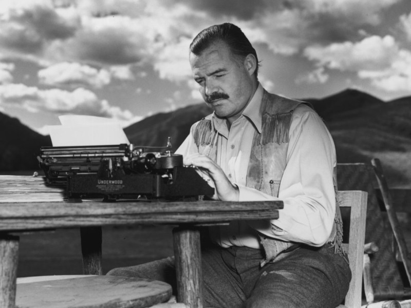 7th October 1939:  EXCLUSIVE American writer Ernest Hemingway (1899 - 1961) works at his typewriter while sitting outdoors, Idaho. Hemingway disapproved of this photograph saying, 'I don't work like this.'  (Photo by Lloyd Arnold/Hulton Archive/Getty Images)