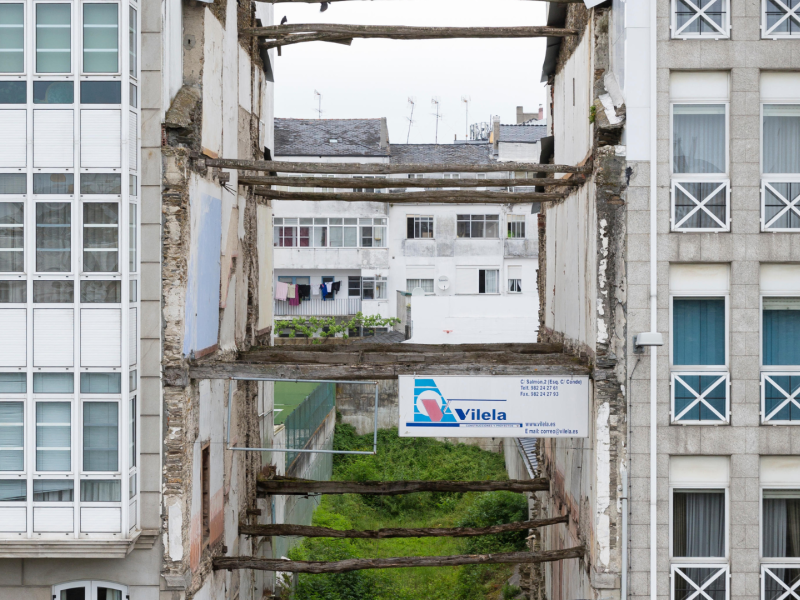 Vigas rústicas apuntalan los edificios que rodean un solar vacío a lo largo de la Ronda da Muralla en Lugo