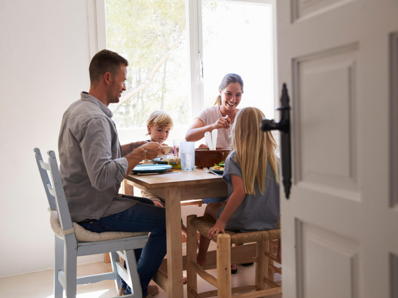 Familia comiendo en la mesa en una habitación soleada