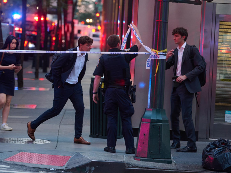 Los peatones caminan a través de una barricada mientras los agentes de policía de la ciudad de Nueva York responden a un incidente con un tirador activo en el centro de la ciudad, que ocurrió dentro de 345 Park Ave, en Nueva York.