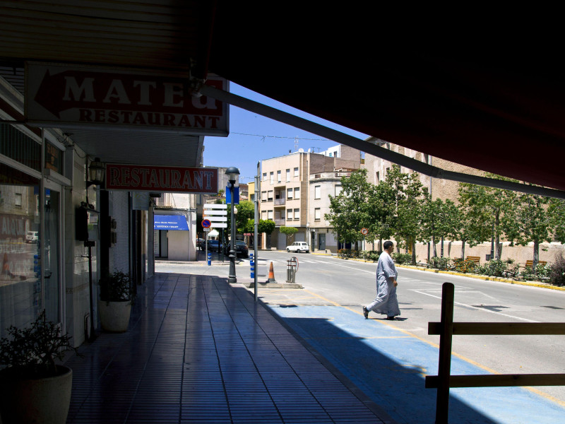 Un hombre con chilaba cruza una calle desierta en verano en Benicarló