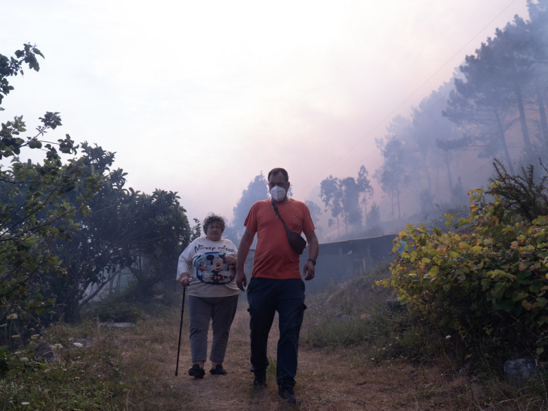 Dos personas huyen del fuego, a 5 de agosto de 2025, en Ponteceso, A Coruña, Galicia (España).