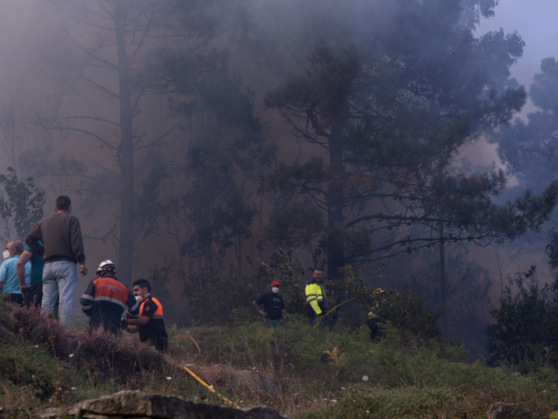 Varias personas tratan de extinguir el fuego, a 5 de agosto de 2025, en Ponteceso, A Coruña, Galicia (España).