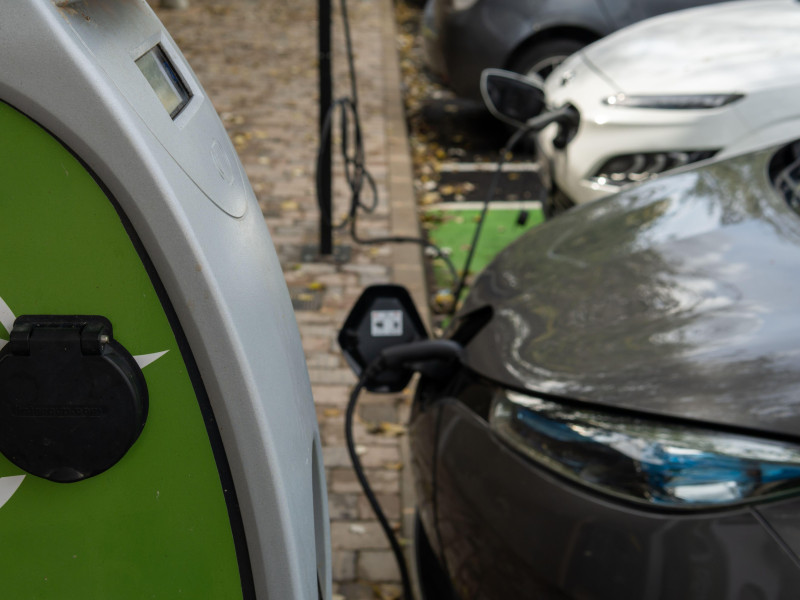 Primer plano de un coche eléctrico Renault de color oscuro en un punto de carga eléctrica cargando la batería. Energía renovable.