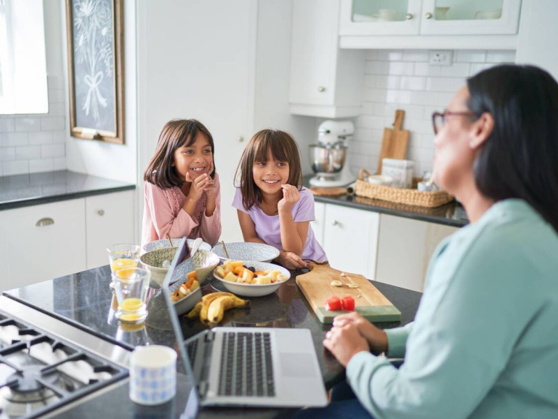 Niñas viendo a su madre trabajar en la cocina