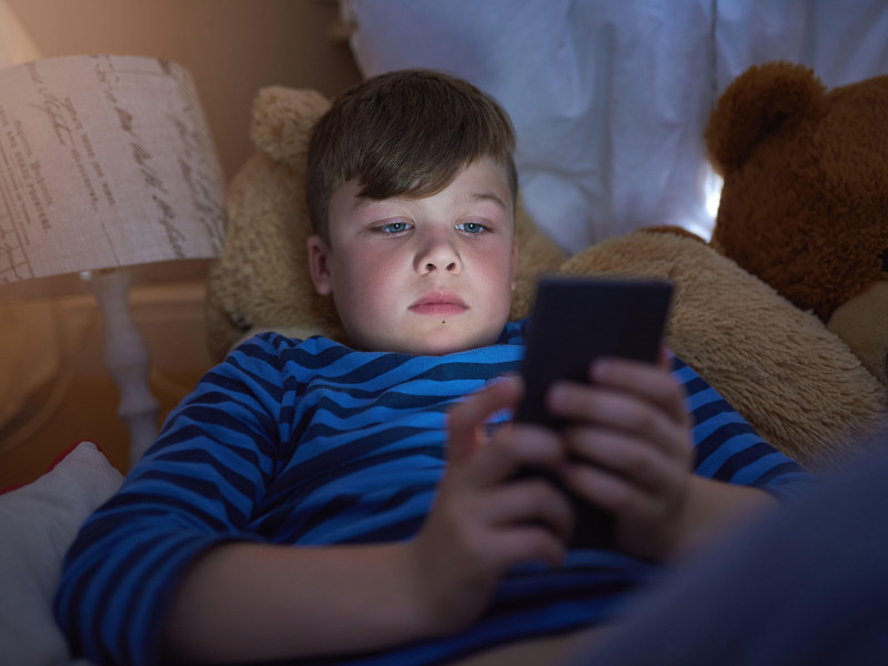 Un niño usando su teléfono móvil antes de dormir