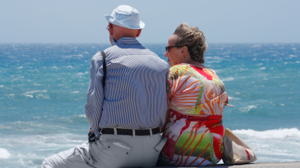 Pareja jubilada mirando al mar en un día ventoso en España
