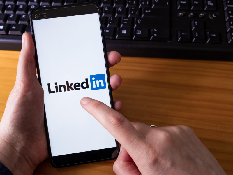 Una mujer sostiene un teléfono inteligente con la aplicación LinkedIn en la pantalla.