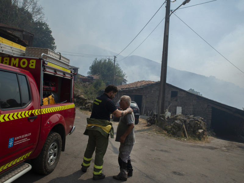 Manuel Fernándes Bahía (delante) y un bombero en la aldea de Teixeira (Maceda) de spués de la noche con el fuego alrededor de la aldea