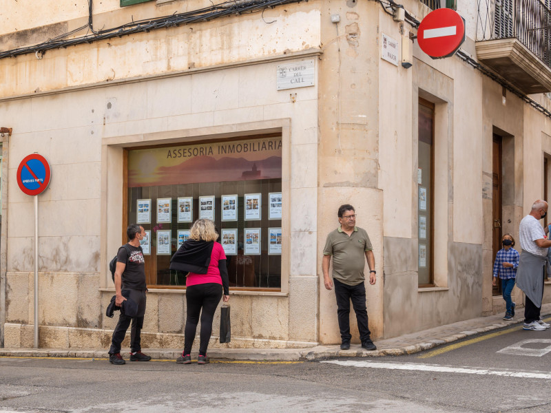Vista general de una agencia inmobiliaria con gente mirando el escaparate en Porreres, España