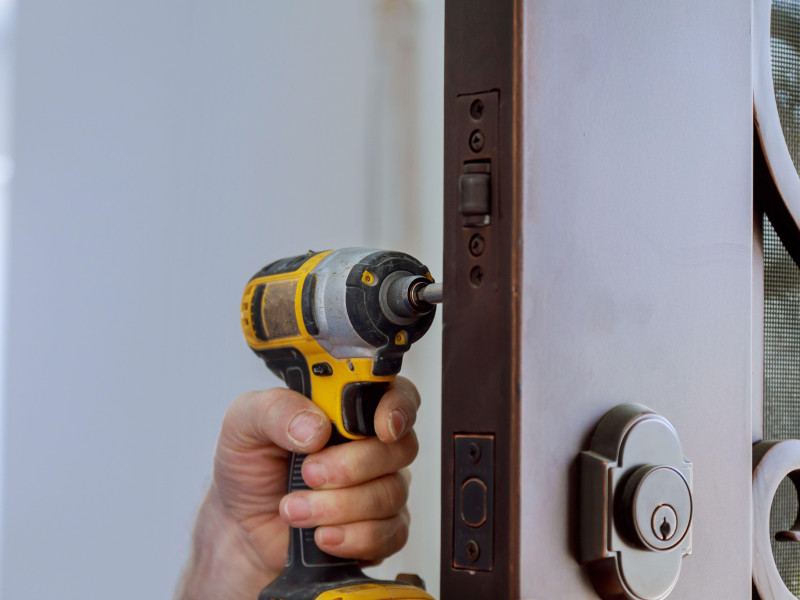 Cerrajero al instalar una nueva cerradura de puerta de casa, la mano sostiene el destornillador