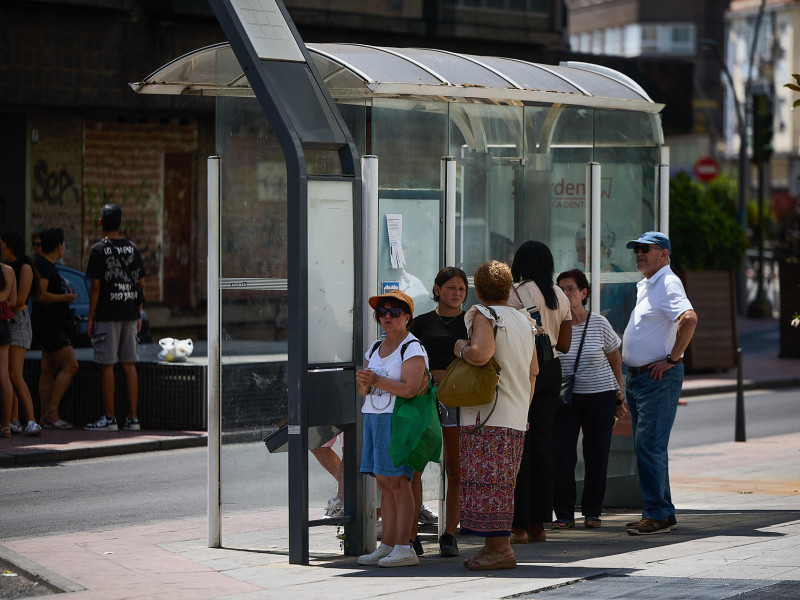 Unas personas esperan a un autobús a la sombra de una parada en una terraza de la localidad toledana de Talavera de la Reina