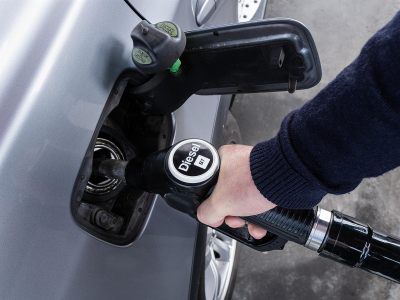 Mano sosteniendo una boquilla de diésel para repostar un coche en una gasolinera