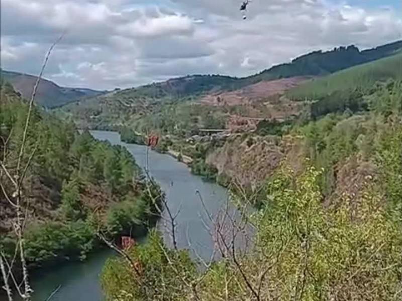 Un helicóptero de extinción capta agua en el río para sofocar el incendio que afecta a Quiroga (Lugo)