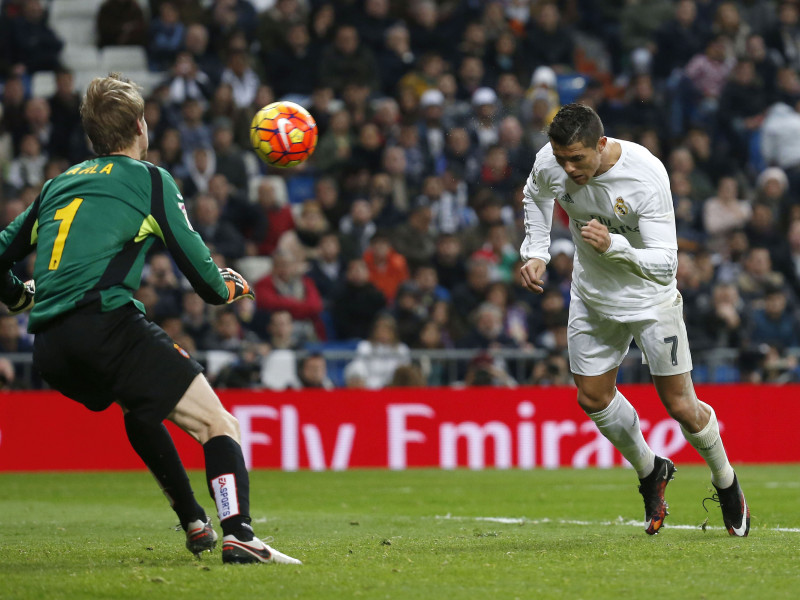 El delantero portugués del Real Madrid, Cristiano Ronaldo (d), cabecea un balón ante el guardameta lituano del Espanyol, Giedrius Arlauskis, para conseguir el quinto gol del equipo blanco, durante el encuentro correspondiente a la jornada 22 de primera división, que han disputado esta noche en el estadio Santiago Bernabéu, en Madrid. EFE/Juan Carlos Hidalgo.