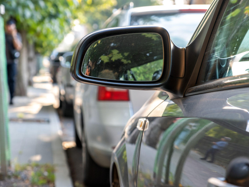 Espejo retrovisor de un automóvil estacionado cerca de la acera al costado de la calle
