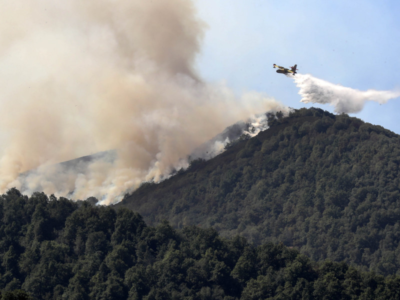 Un avión descargando agua sobre las llamas en un incendio de Asturias
