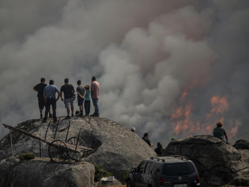 Varias personas observan el incendio forestal declarado ayer en Avión (Ourense)