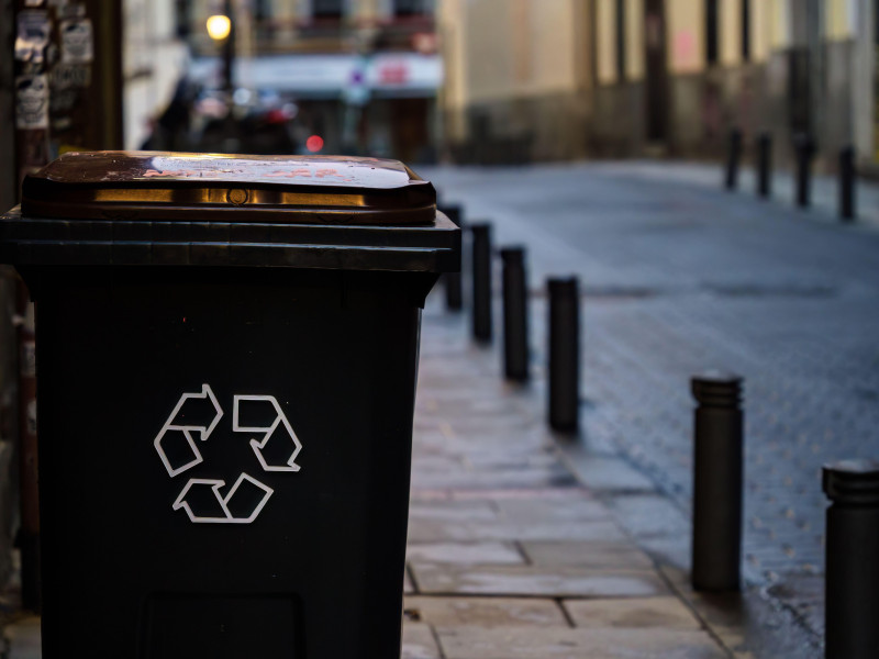 Papelera negra con el símbolo de reciclaje al lado de la calle en Madrid