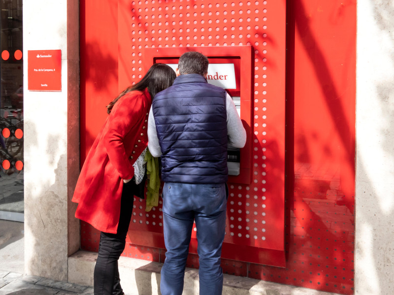 Pareja utilizando un cajero automático en una sucursal del Banco Santander en Sevilla