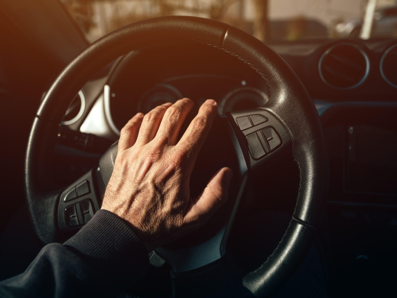 Conductor colocando una mano sobre la bocina del volante del automóvil