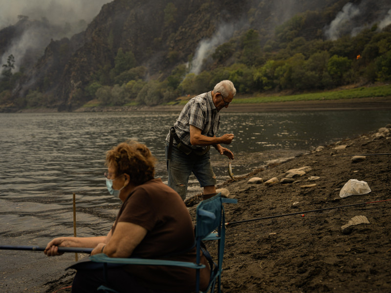 Una pareja pesca mientras el monte arde en Galicia
