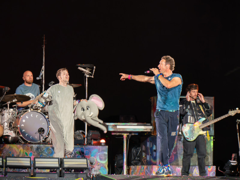 La banda Coldplay se ve en el escenario con un miembro de la audiencia vestido con un disfraz de elefante en el estadio de Wembley.