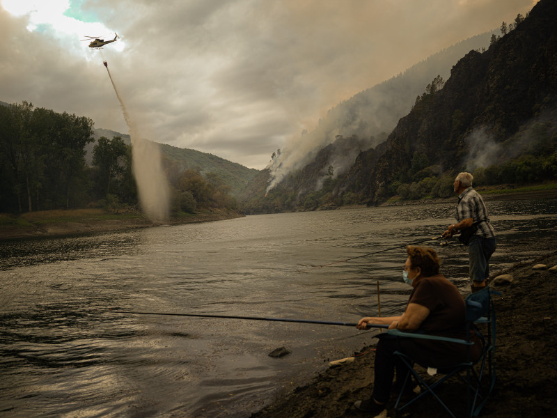 Una pareja observa cómo un helicóptero capta agua durante la extinción