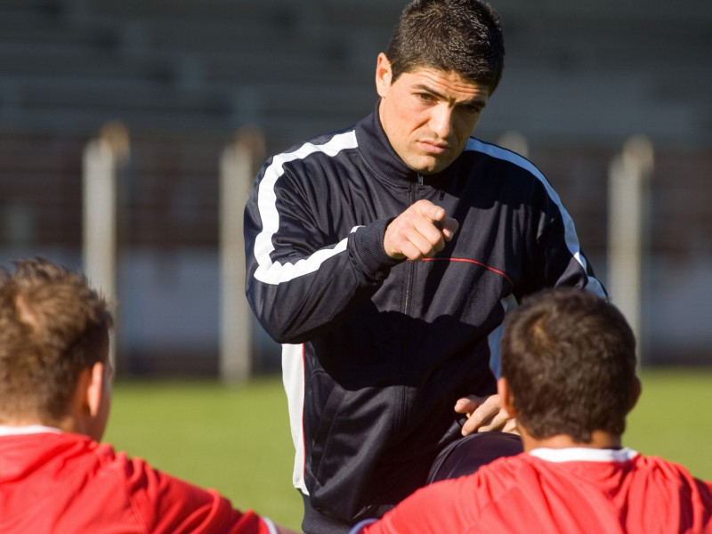 Entrenador de un equipo de fútbol dando indicaciones a sus futbolistas