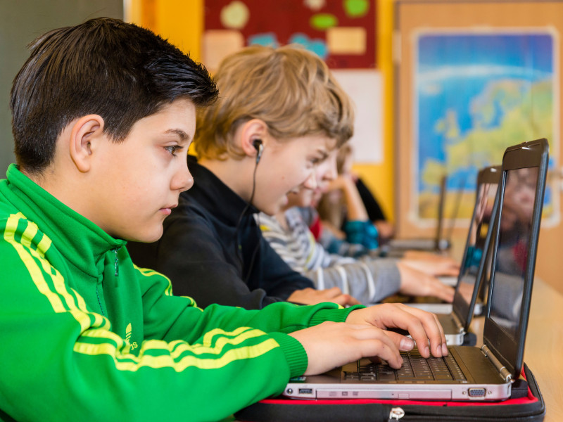 Los estudiantes de secundaria (de unos 12 años) trabajan con sus computadoras portátiles en su aula.