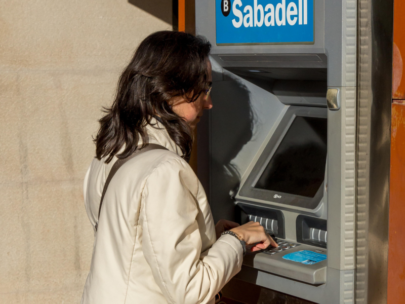 Una joven saca dinero de un cajero automático del Banco Sabadell en España