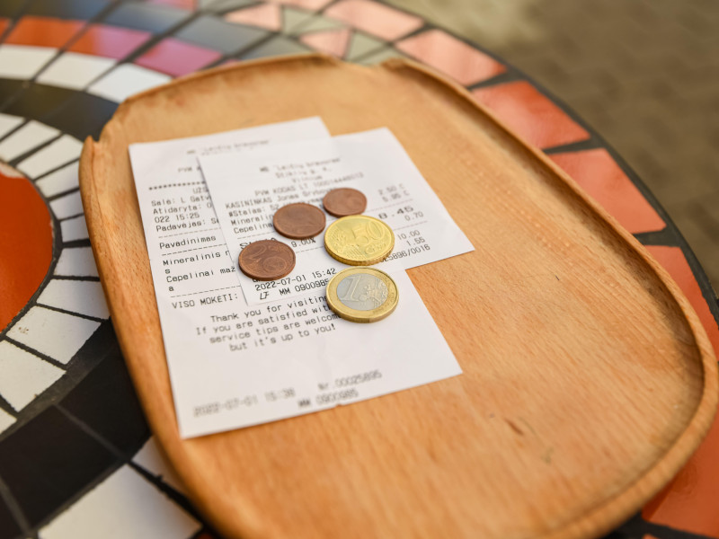 Bandeja de madera en un café con factura de pago y cambio en monedas de euro. en la calle
