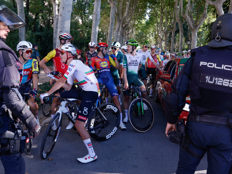 Agentes de la Policía Nacional, junto a los ciclistas de la última etapa de La Vuelta, a su entrada en Madrid