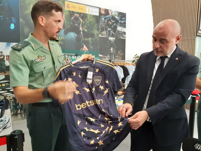El jefe de la Unidad Orgánica de la policía judicial en Lleida, el capitán Antoni Lorenzo, y el delegado del Gobierno en Cataluña, Carlos Prieto, muestran una de las camisetas falsificadas