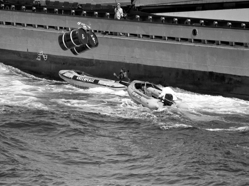 Histórica imagen de una de las lanchas de Greenpeace a punto de ser hundida por los bidones nucleares arrojados desde uno de los buques