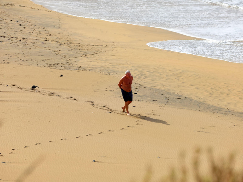 Un jubilado camina descalzo por la playa de Piedra, El Cotillo, Fuerteventura