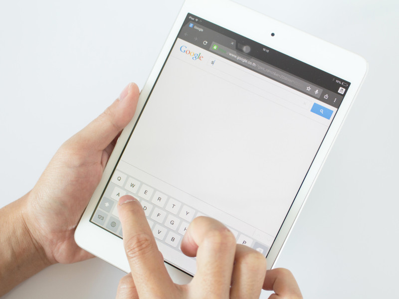 Las manos de un hombre apuntan a un dispositivo de pantalla táctil con la búsqueda de Google.