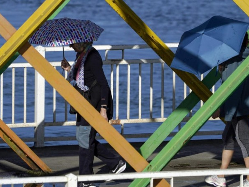 Dos personas cruzan el puente con los paraguas abiertos bajo la lluvia