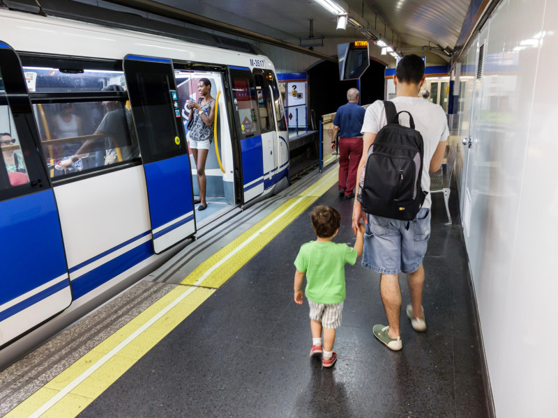Un padre caminando por el andén del metro de Madrid con su hijo