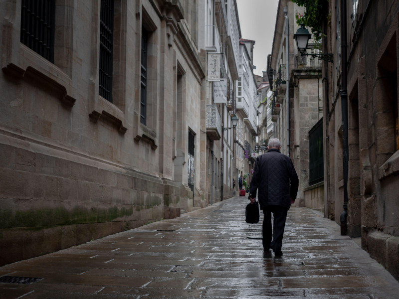 Un anciano solitario camina por una calle del casco antiguo de Santiago de Compostela