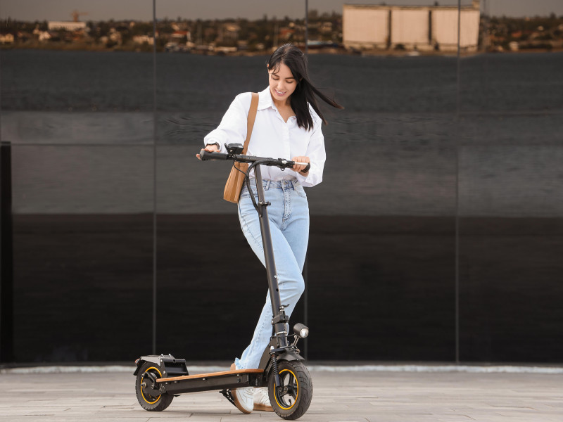 Joven empresaria montando patinete eléctrico al aire libre