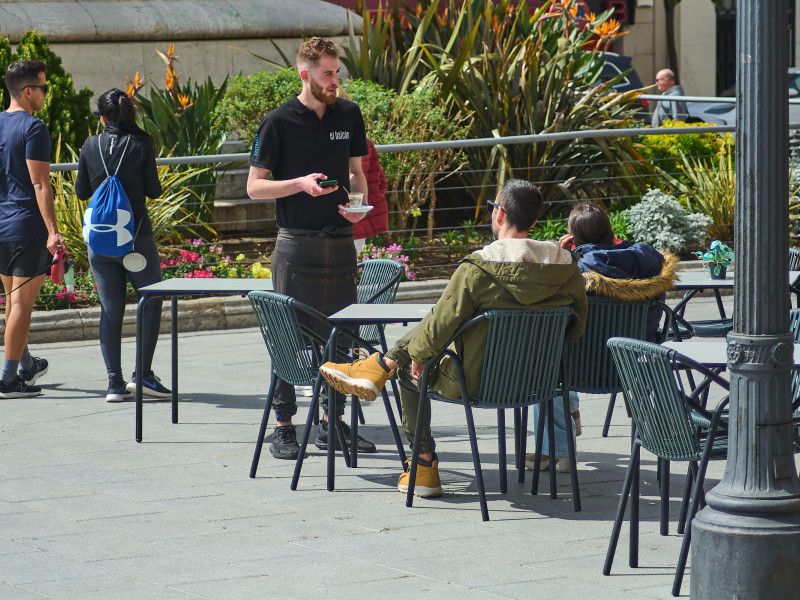 Un camarero sirve a una joven pareja que está disfrutando en un café al aire libre en Tarragona